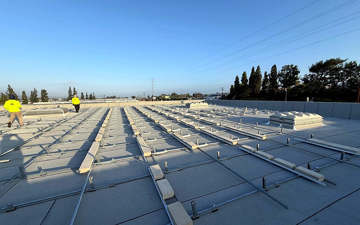 Current Energy crew laying out racking on a commercial roof at sunrise