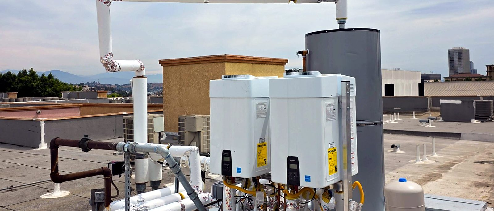 Rooftop tankless and storage water-heating plant at a multifamily building, installed by Current Energy