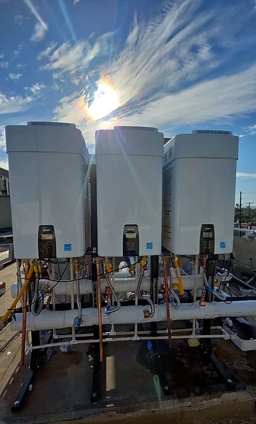 Three Navien tankless water heaters on a rooftop stand