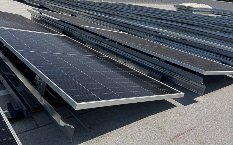Tilted solar panel rows on a flat warehouse roof