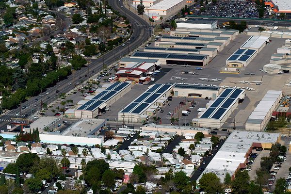 Van Nuys Airport hangar roofs with solar arrays among the surrounding neighborhood