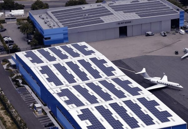 Solar panels across a hangar roof with a jet parked alongside